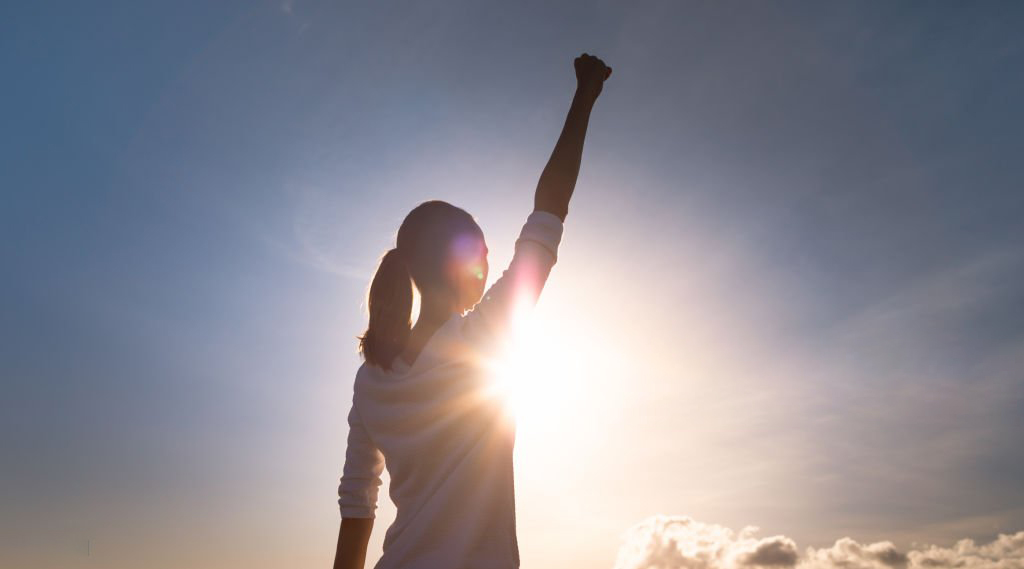 Woman with fist up feeling strong, powerful and determined.